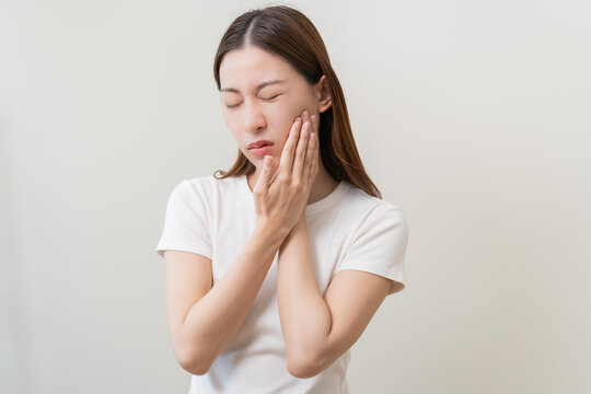 Face expression suffering from sensitive teeth and cold, asian young woman, girl feeling hurt, pain touching cheek, mouth with hand. Toothache molar tooth, dental problem isolated on white background.