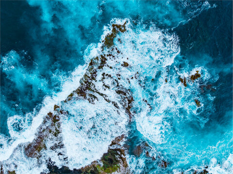 Aerial view of the rugged coastline and crashing waves at Mosteiros Beach, showcasing the deep blue Atlantic waters and volcanic rock formations in Mosteiros, Acores, Portugal.