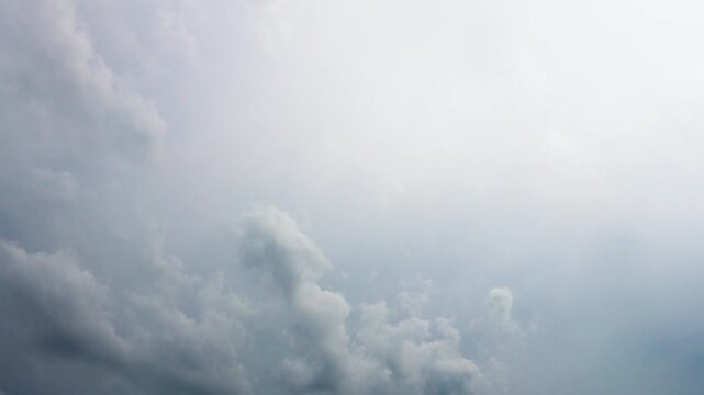 Time lapse of soft white and gray clouds moving across a bright daytime sky