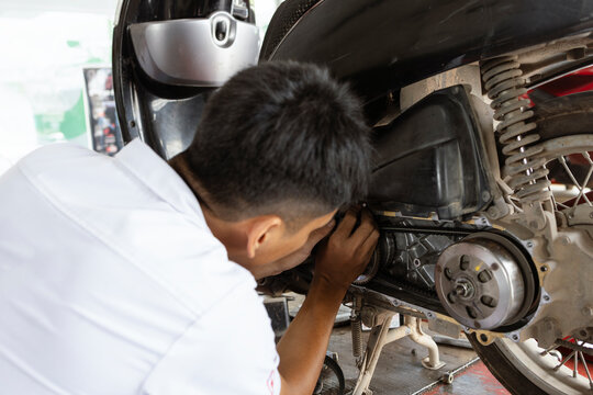 Motorcycle Mechanic Performing Rear Wheel Maintenance in Service Workshop