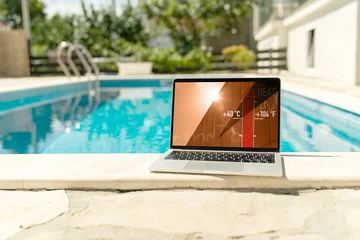 Fototapeten Musik Laptop by the swimming pool displaying a forty-degree high temperature warning during a heatwave  © scharfsinn86
