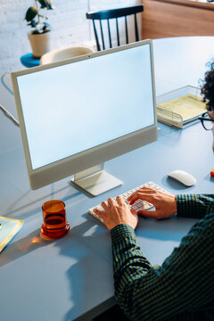 A man uses a computer with a white screen 