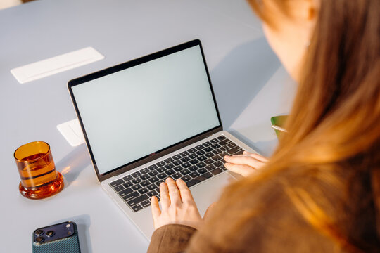 A woman using a laptop with a white screen