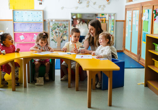 Teacher engaging with diverse young children in kindergarten classroom
