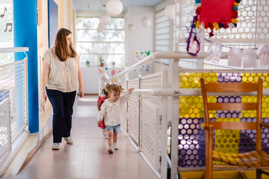 Teacher leading preschool children in kindergarten hallway