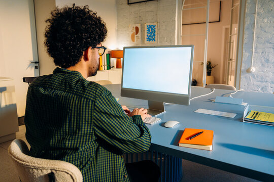 A man uses a computer with a white screen 