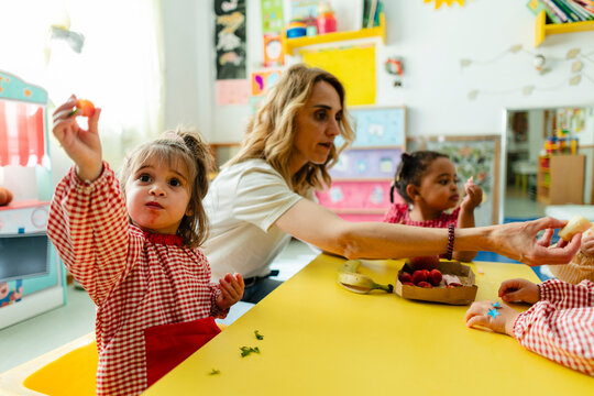 Toddler girl holding fruit learning healthy eating habits