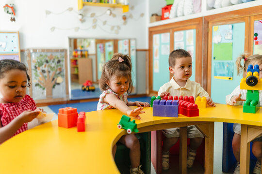 Diverse toddlers playing with colorful building blocks at preschool