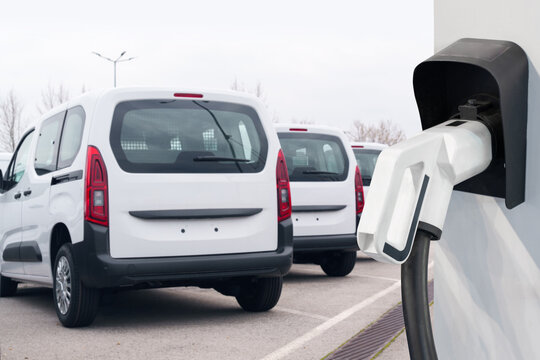 Electric vehicles charging station on a background of a row of vans. Green transportation concept
