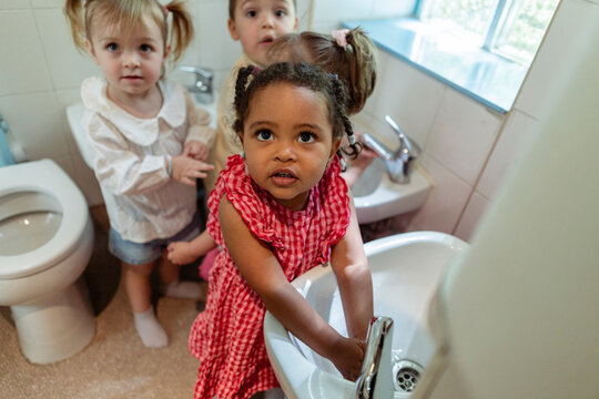 Children learning hand washing hygiene in kindergarten bathroom