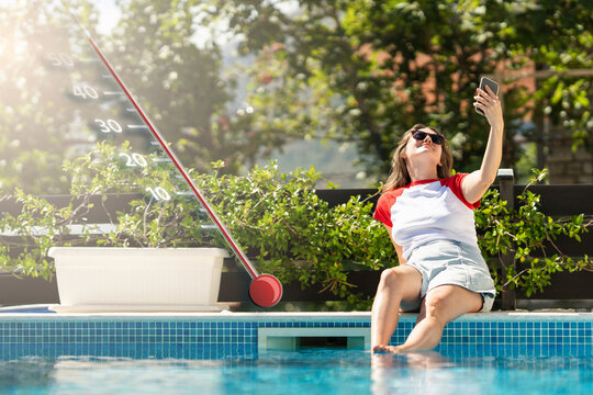 Woman checking smartphone by the swimming pool during an extreme summer heatwave