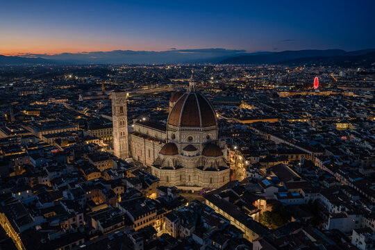Aerial view of the illuminated Florence Cathedral and Giotto's Campanile rising above the historic rooftops of Florence, Tuscany, Italy.