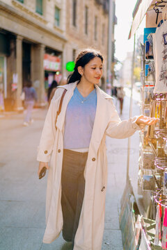 A woman chooses a postcard on a city street