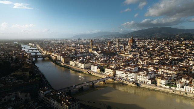 Aerial view of the historic city of Florence with the Arno River, Ponte Vecchio, and the Duomo cathedral under a clear sky in Florence, Tuscany, Italy.