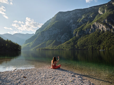 A woman takes a cellphone photo on a lake