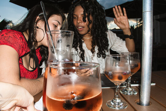 Two Friends Laughing While Sharing Sangria at Sunset