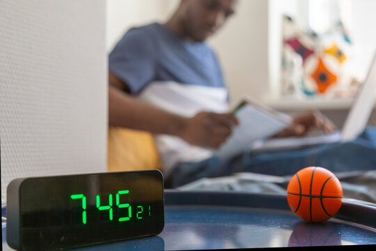 Person studying with digital clock and basketball in dormitory