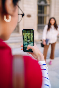 A woman photographing a friend on a mobile phone