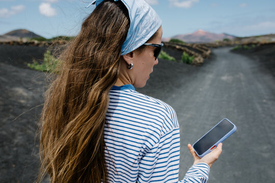 Woman with blue bandana and phone in Lanzarote's volcanic landscape