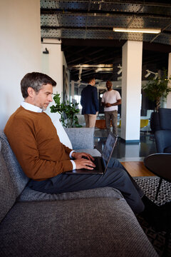 Man works on a laptop in a lounge area