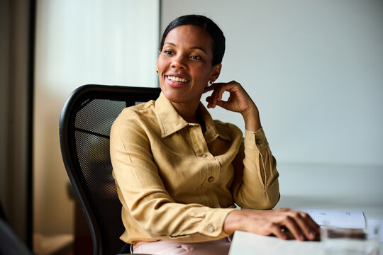 Businesswoman sits back at the office, smiling