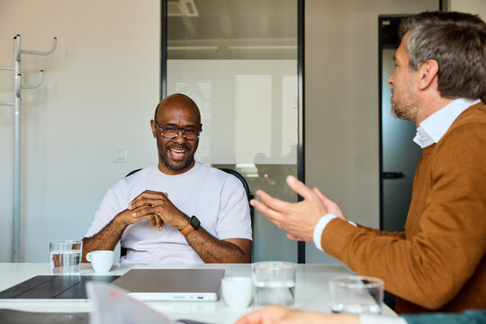Two men have a cheerful conversation at the office
