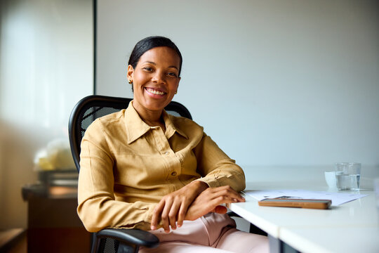 Businesswoman sits back at the office, smiling