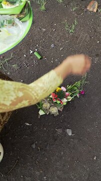 Balinese Woman is performing Traditional Offering Ritual or Worship Ritual at home during Kuningan Ceremony in Bali. Religion, Culture, and Travel Concept. 4K Footage