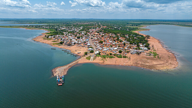 Aerial view of the town on a peninsula in Lake Volta, with a ferry at the pier, surrounded by rural rooftops in Kwahu Afram Plains South, Eastern Region, Ghana.