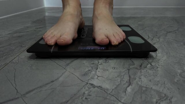 Women's feet stand barefoot on electronic floor scales to check their weight