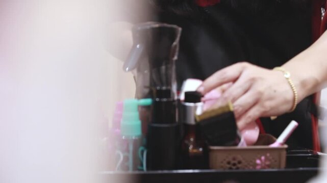 실내 미용실 작업대 위에서 다양한 미용 도구와 소품들을 정리하거나 사용하는 인물의 손동작을 가깝게 포착한 클로즈업 동영상 클립입니다.