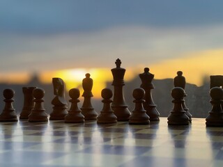 Silhouette of chess pieces on a board with a cityscape at dusk, evoking a sense of strategy and focus.  © kareem