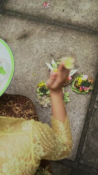 Balinese Woman is performing Traditional Offering Ritual or Worship Ritual at home during Kuningan Ceremony in Bali. Religion, Culture, and Travel Concept. 4K Footage
