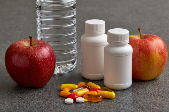 Health items on a table with red apples and water