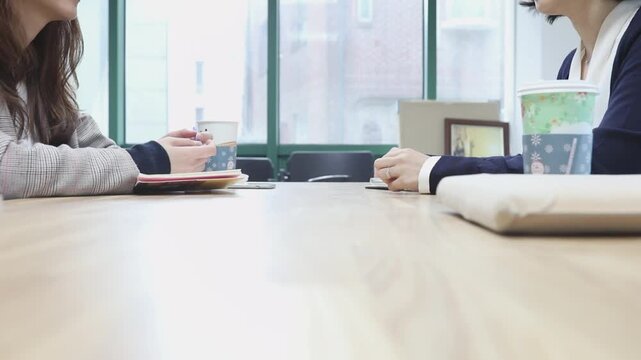 사무실 회의 테이블에 마주 앉아 대화를 나누는 두 인물의 모습을 담은 장면으로, 카메라가 부드럽게 이동하는 팬 샷 동영상 클립입니다.