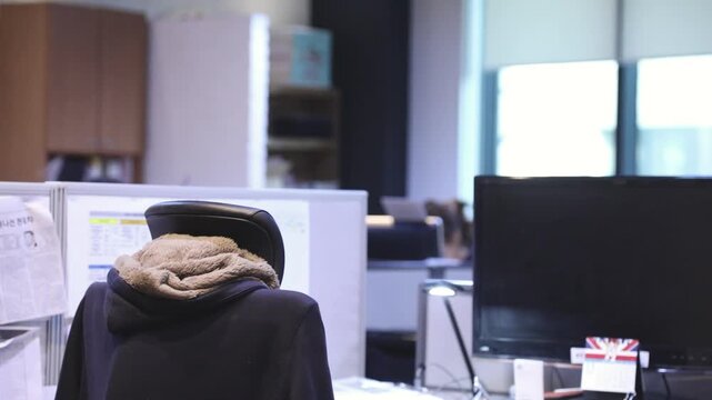 실내 사무실에서 업무를 진행 중인 인물의 뒷모습과 함께 사무 공간의 일상적인 배치와 환경을 차분하게 포착한 동영상 클립입니다.