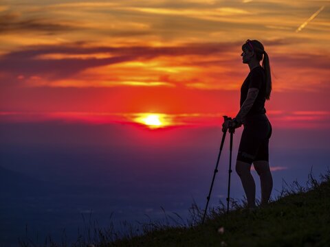 Silhouette of a young slender woman with hiking poles on a mountain meadow at sunset, Schlenken, Bad Vigaun, Salzburg province, Austria