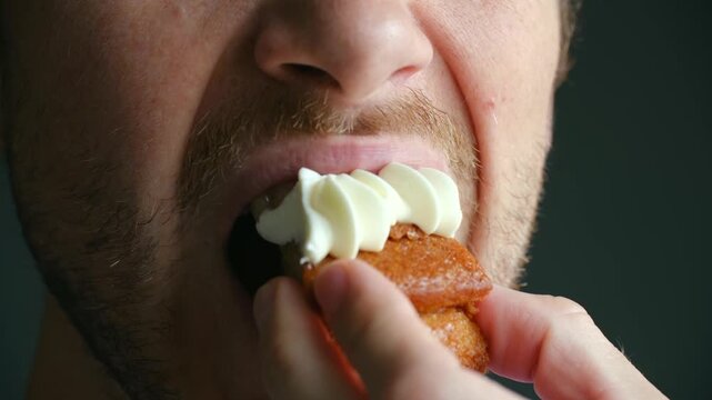Extreme close up bearded man mouth opening wide to eat sweet, delicious carrot cake with cream cheese frosting, chewing with pleasure, enjoying dessert taste. Man eating carrot cake with cream 
