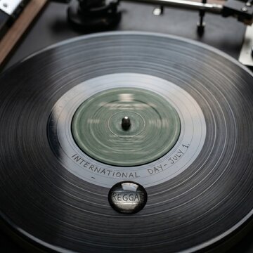 Macro Studio Photography of Vintage Vinyl Record with Etched International Reggae Day Text and Condensation Drop Magnifying Glass

