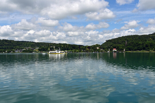 View of placid Lake Worthersee near Klagenfurt, Austria with summer cloudscape reflected in calm water.