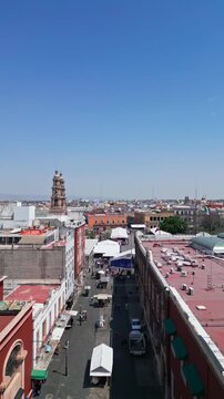 Aerial drone flight over the rooftops and church towers of the historic center of Aguascalientes on a sunny day, central Mexico.