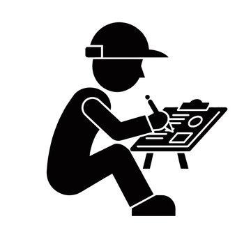 Engineer sits at a desk while meticulously writing notes on a detailed technical clipboard plan.