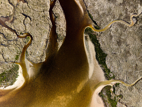 Aerial view of the winding tidal channels and sandy banks of Emu Point, featuring dark water patterns and coastal vegetation in Emu Point, Western Australia, Australia.