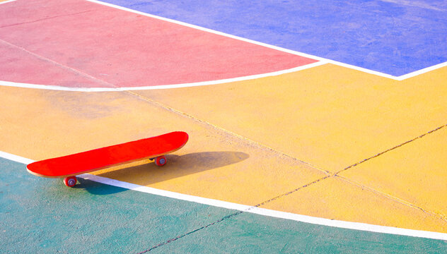 Skateboard on vibrant outdoor sports court with colorful geometric pattern on the ground. Creative urban sport and youth culture lifestyle concept 
