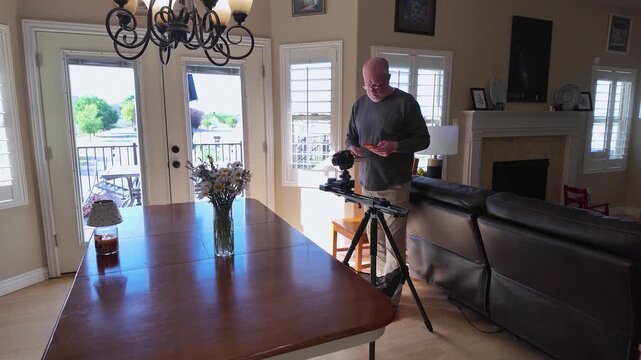 A man setting up a professional motorized dolly slider track and tripod inside a living room
