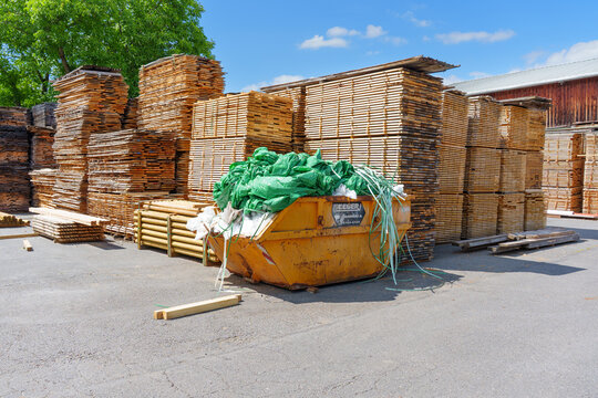 Otzberg-Lengfeld, Germany - June 15, 2026: Stacked Sawn Wood and Waste Skip in Otzberg-Lengfeld Germany