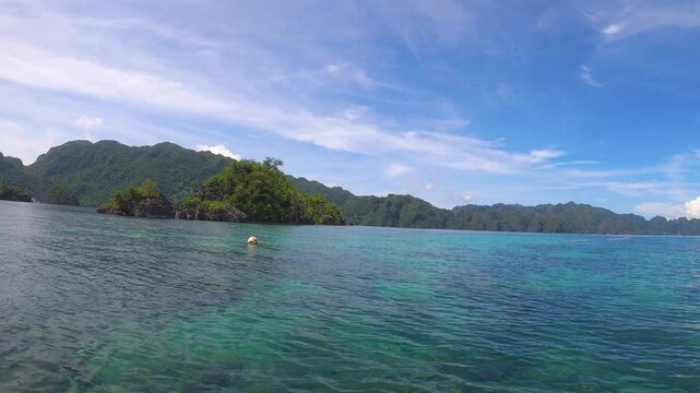 slow motion of horizontal pane view look out to shallow blue green turquoise peaceful lagoon from a small boat to mountains and boats far away at small fishing village of Siete Pecados Marine Park Cor