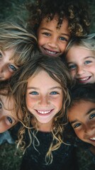 Fototapeta premium A diverse group of smiling children lie together on grass, their joyful faces forming a vibrant background for themes of unity and childhood innocence.