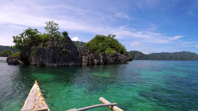 slow motion of still view look out to shallow blue green turquoise peaceful lagoon from a small boat to coral rocks at Siete Pecados Marine Park Coron Philippines during sunny blue sky good day with b