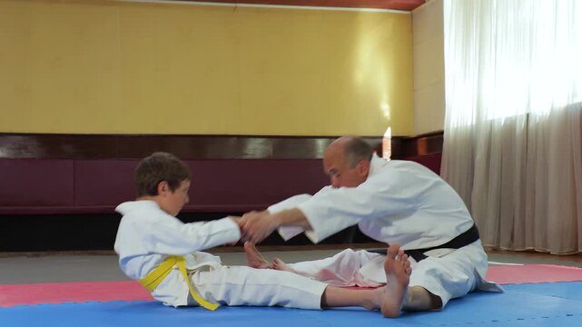 A trainer and a little athlete perform stretching exercises